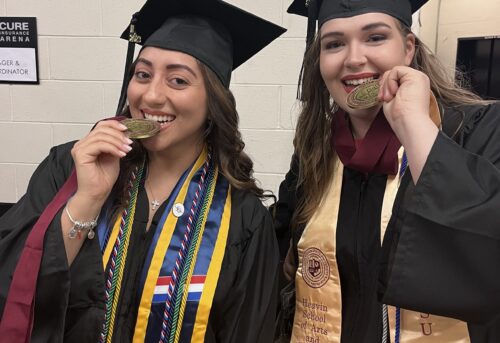 Two Thomas Edison State University graduates biting their medals.